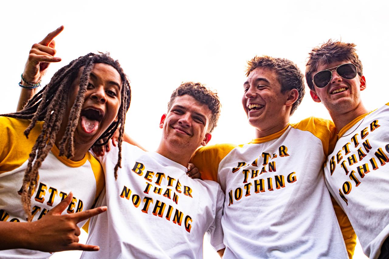 The four members of Better Than Nothing laughing together in their yellow and white BTN shirts.